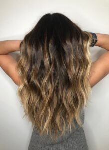 Dark brunette hair with dimensional balayage highlights and beach waves by Leslie Shores