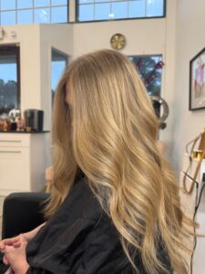 Long golden blonde highlighted hair styled in soft waves by Haley Tucker