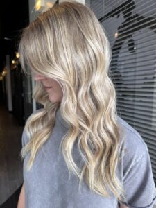 Dark root melt into bright, dimensional blonde balayage styled in long layered waves by Brooke Bennett, Mount Juliet, TN hairstylist